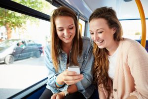 Two Young Women Reading Text Message On Bus